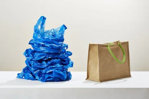 un teanc de pungi de plastic lângă o pungă de cumpărături reutilizabilă